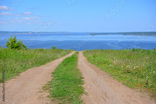 countryside road on the hill with river and blue sky on background