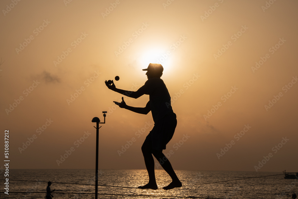 silhouette of a person juggling on a tightrop 