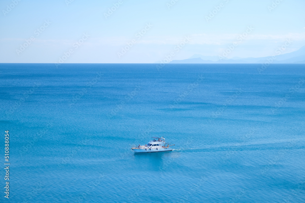 White yacht floats on blue water in the sea against the backdrop of mountains on a sunny day White yacht floats on blue water in the sea against the backdrop of mountains on a sunny day