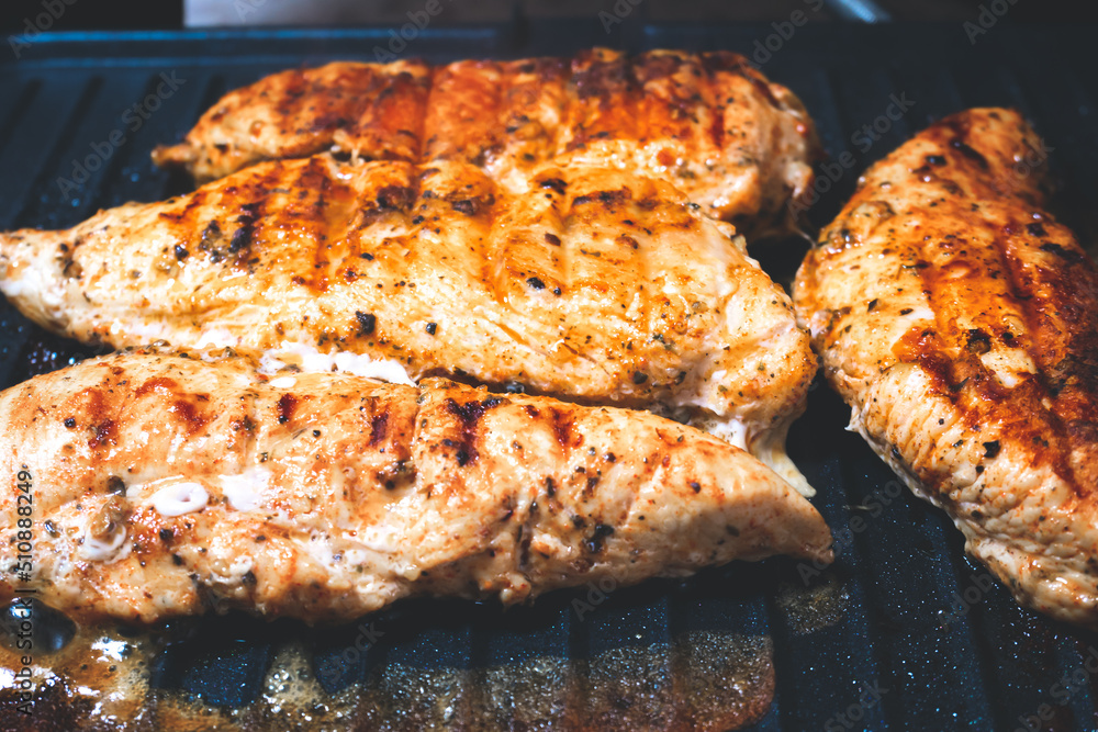 Delicious juicy chicken steak seasoned with herbs and spices is fried in a grill. Barbecue party.