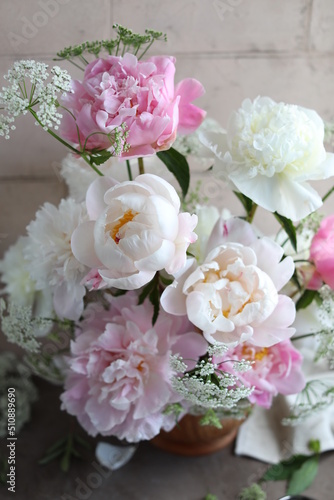 Lush bouquet of white and pink peonies. Floral arrangement of seasonal garden flowers in a wooden bowl. Floral summer still life. © Susie Foods