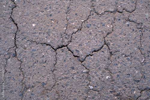 Old worn and cracked asphalt with cracks. Asphalt cracked road dark texture.