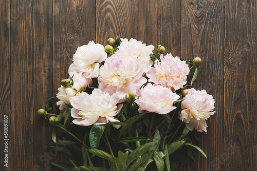 Bouquet white pink peonies flowers on a wooden background. Flat lay minimalist aesthetic peonies. Beautiful card for Mother's Day or Women's Day