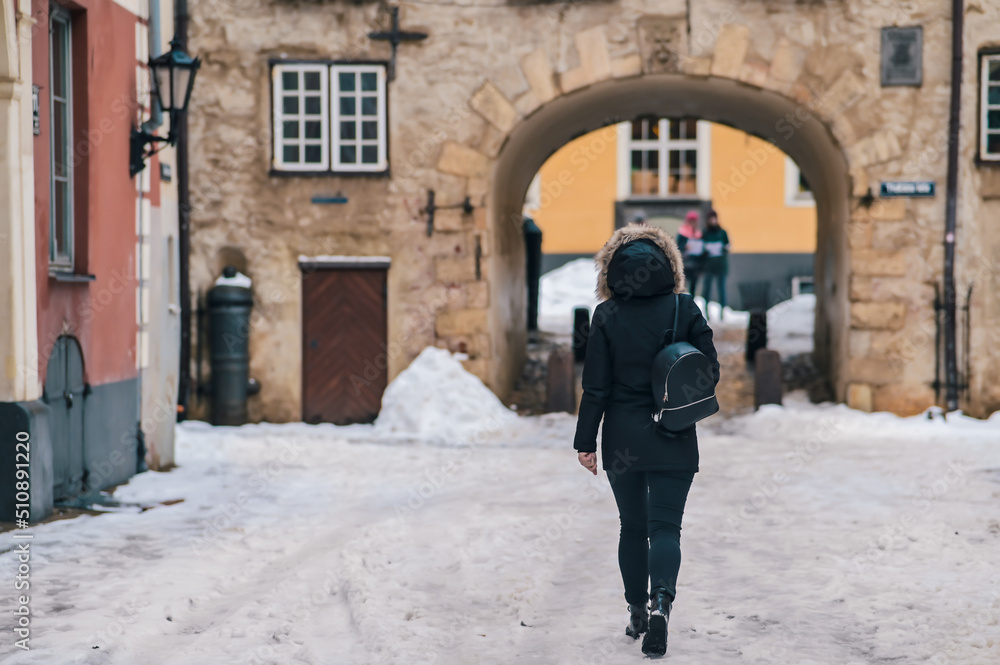 Urban portrait of a woman in a coat walking down a snowy street. Street lifestyle and urban environment.