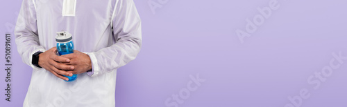 Photos cropped view of african american man in trendy sportswear holding sports bottle isolated on purple, banner