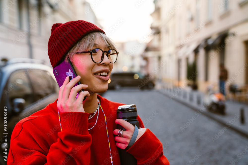 Fototapeta premium Asian boy laughing and talking on mobile phone at street