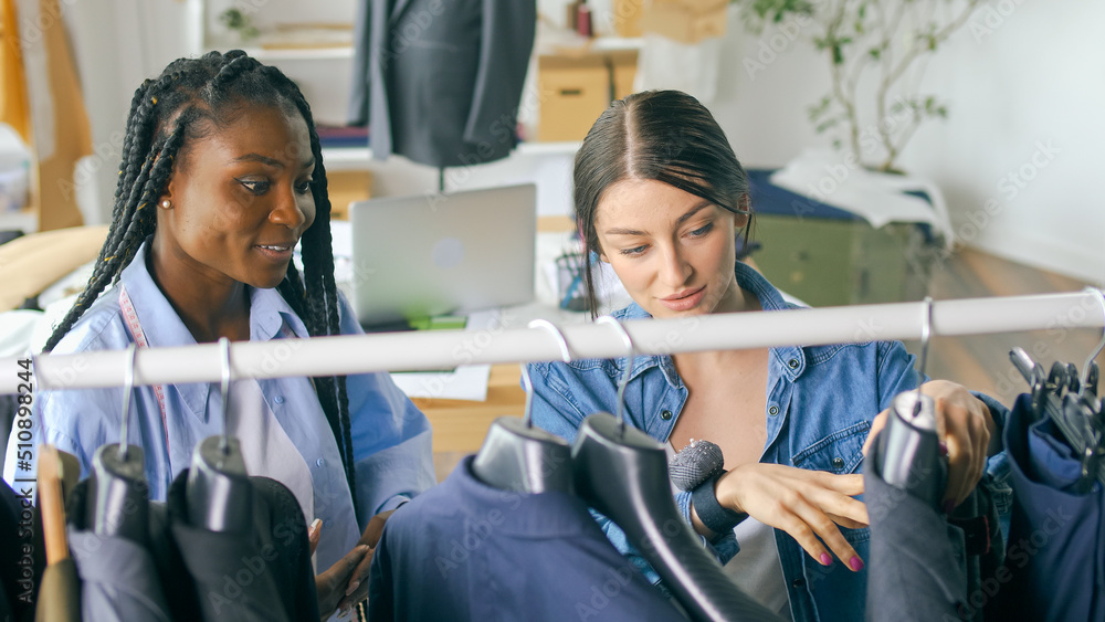 Professional Designer Makes Measurements of Clothes on a Mannequin. African American Colleague Works with a Tablet. Creative Business and Technology in a Light Studio. Apparel Design Startup Concept. Professional Designer Makes Measurements of Clothes on a Mannequin. African American Colleague Works with a Tablet. Creative Business and Technology in a Light Studio. Apparel Design Startup Concept.