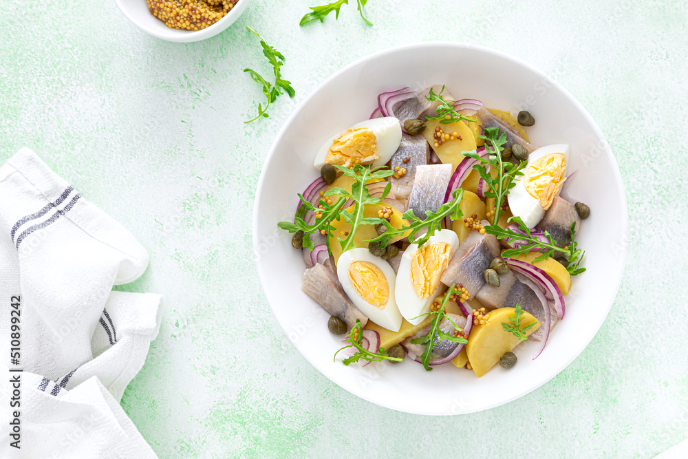 Herring and boiled potato salad with egg, capers and red onion. Top view Herring and boiled potato salad with egg, capers and red onion. Top view