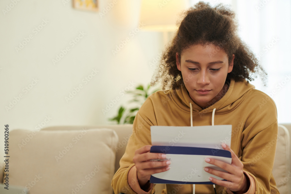 Anxious teenage girl opening acceptance letter from university Anxious teenage girl opening acceptance letter from university