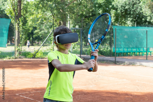 Close up image of boy in vr glasse on tennis court with raquet in his hands. Training process in cyberspace with virtual coach.