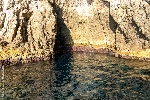 Entrance of sea cave Blue Grotto (Grotta Azzurra) near Isola Bella in Taormina, Sicily, Italy, Europe, EU. Clear magical blue turquoise water surface Ionian Mediterranean sea