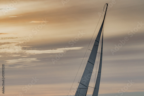 Top of mast of sailing yacht at sunset, orange sky, sail regatta, magic clouds sky