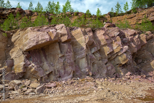 A section of crimson quartzite rock in an old quarry. Kvartsitny village, Karelia photo