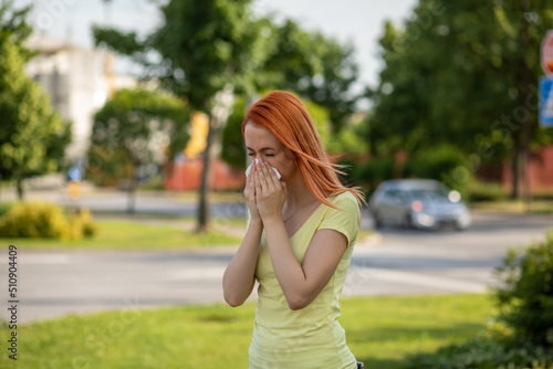 Young redhair woman sneezing in spring. Pollen Allergy symptoms