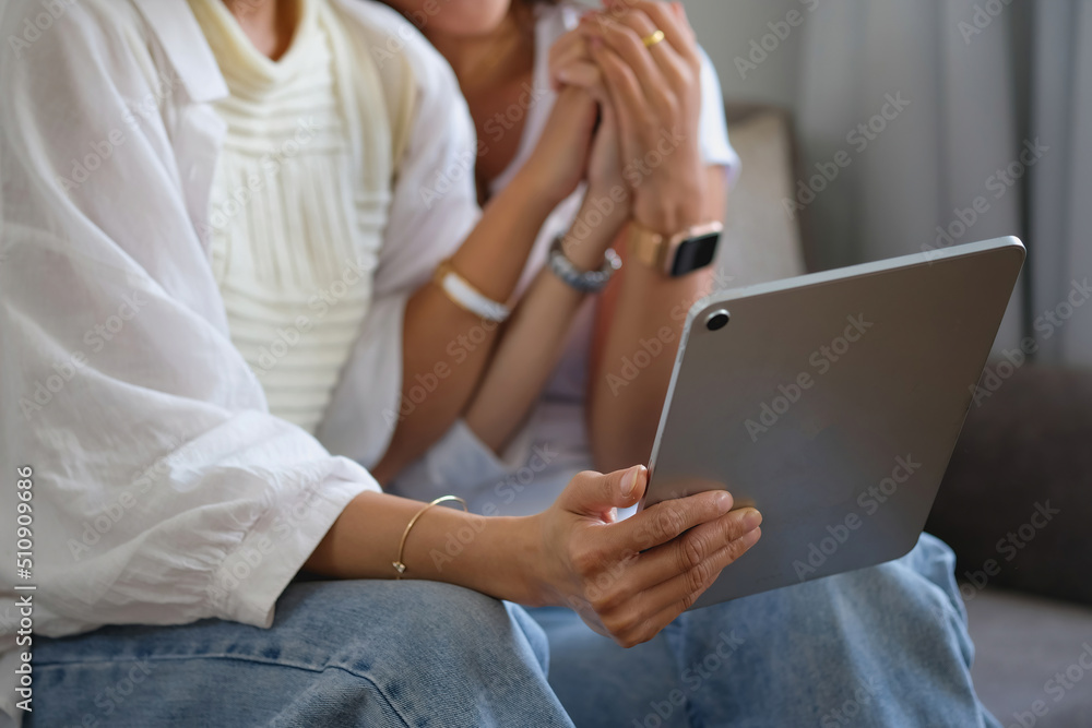 Obraz premium lgbtq, lgbt concept, homosexuality, two beautiful women in love happily playing tablet in a cozy home