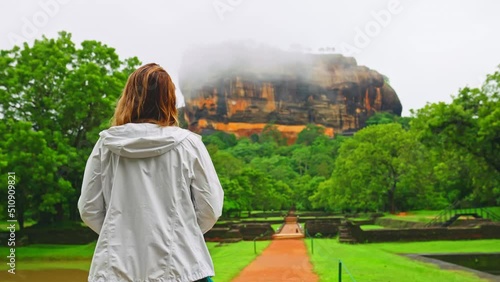 Back view of young tourist woman walking in slow motion on an empty trail towards Sigiriya or Lions Rock, Sri Lanka photo