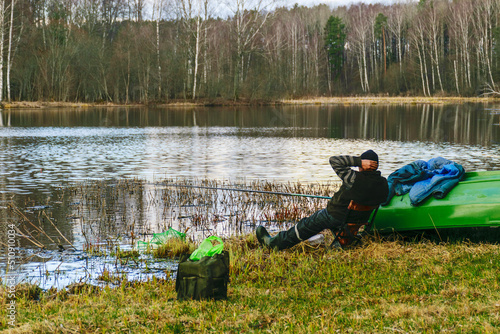 A man resting and fishing on the shore of a lake, fishing for pike, perch, carp, the concept of rural recreation