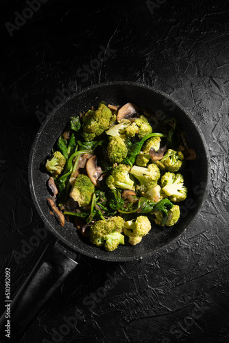 Dish Fried vegetables with mushrooms in a non-stick pan. Broccoli, spinach, onion in olive oil. Cooking healthy food.