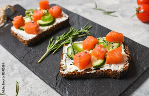 Healthy toasts with rye bread with cream cheese, salmon, fresh cucumber and sesame seeds.