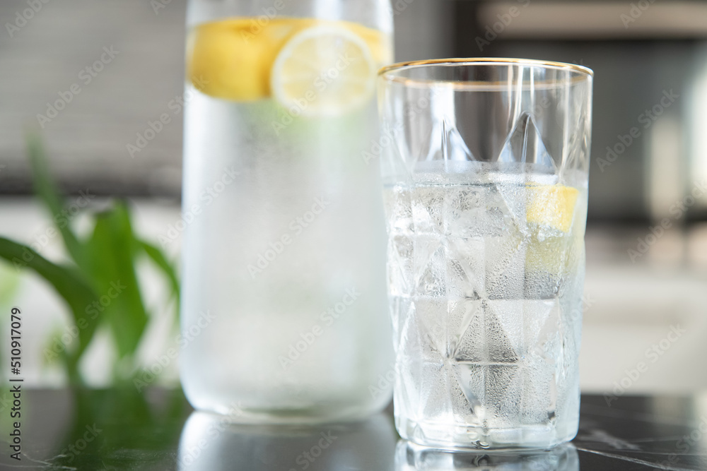 Glass with lemonade with lemon in the kitchen. Summer refreshing drink. Fresh homemade lemonade with lemon slices Glass with lemonade with lemon in the kitchen. Summer refreshing drink. Fresh homemade lemonade with lemon slices