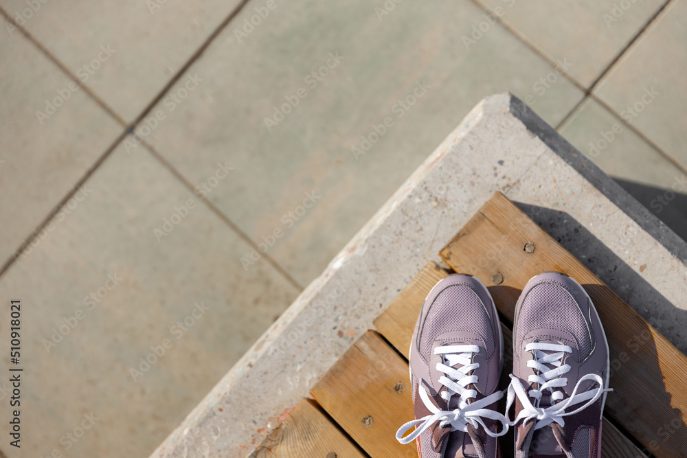 pink new sneakers stand on wooden planks against the background of gray paving stones. Place for text