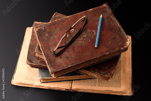 Obraz na płótnie Stack of old worn jewish books in leather binding on open Torah pages on dark background. Closeup. Selective focus. w salonie