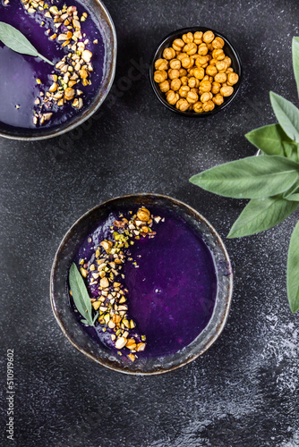 Food photo with bright red cabbage cream soup. With chickpeas and sage leaves are laying nearby. Purple food