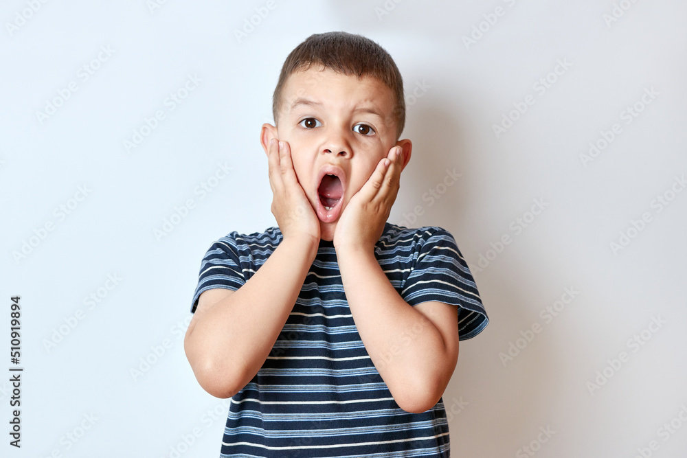 The little boy took his hands fascinatingly to his cheeks, opening his mouth wide. The little boy took his hands fascinatingly to his cheeks, opening his mouth wide.