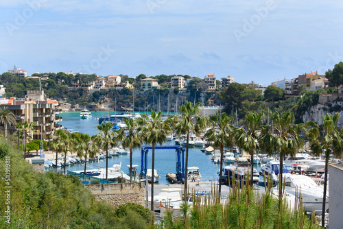 Porto Cristo, Mallorca, Spain - 05.02.2022: Yachts and boats in port of Porto Cristo. Houses on cliffs in background