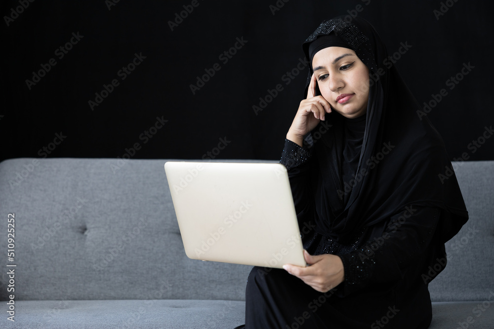 muslim woman using laptop computer and thinking a new idea on sofa and black background muslim woman using laptop computer and thinking a new idea on sofa and black background