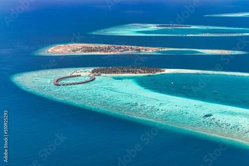 Panoramic landscape seascape aerial view over a Maldives atoll islands. Coral reef, ocean lagoon with white sandy beach seen from above. Luxury water villas, exotic travel destination, summer tourism