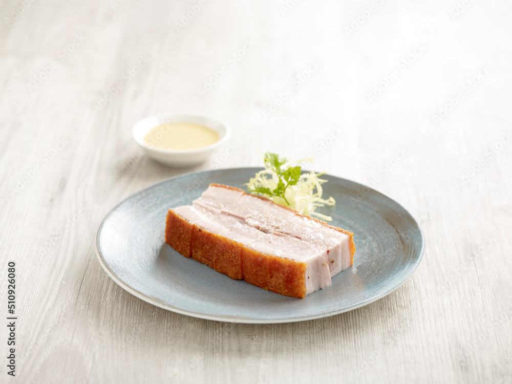 Crackling Pork Belly Served in a dish isolated on wooden board side view on grey background