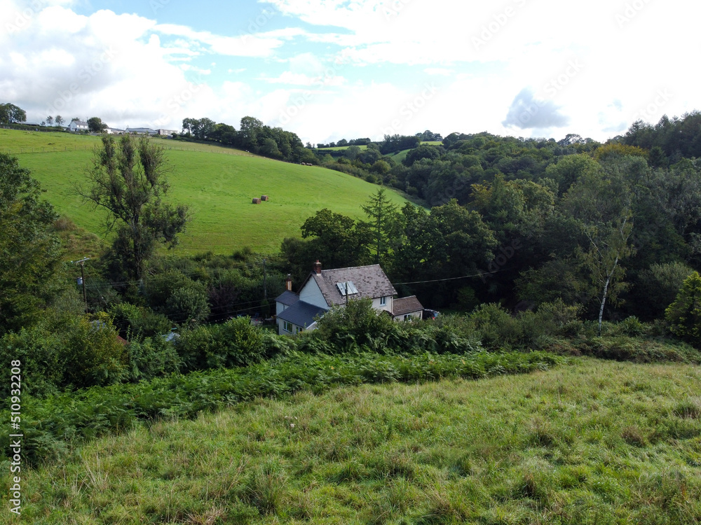 A Devon farmhouse enstles in a valley between fields