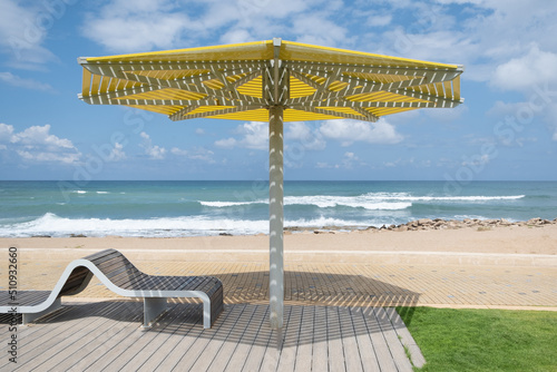 Modern promenade in israel  seafront of the mediterranean sea with a sunbed and a beach umbrella sunshade.
