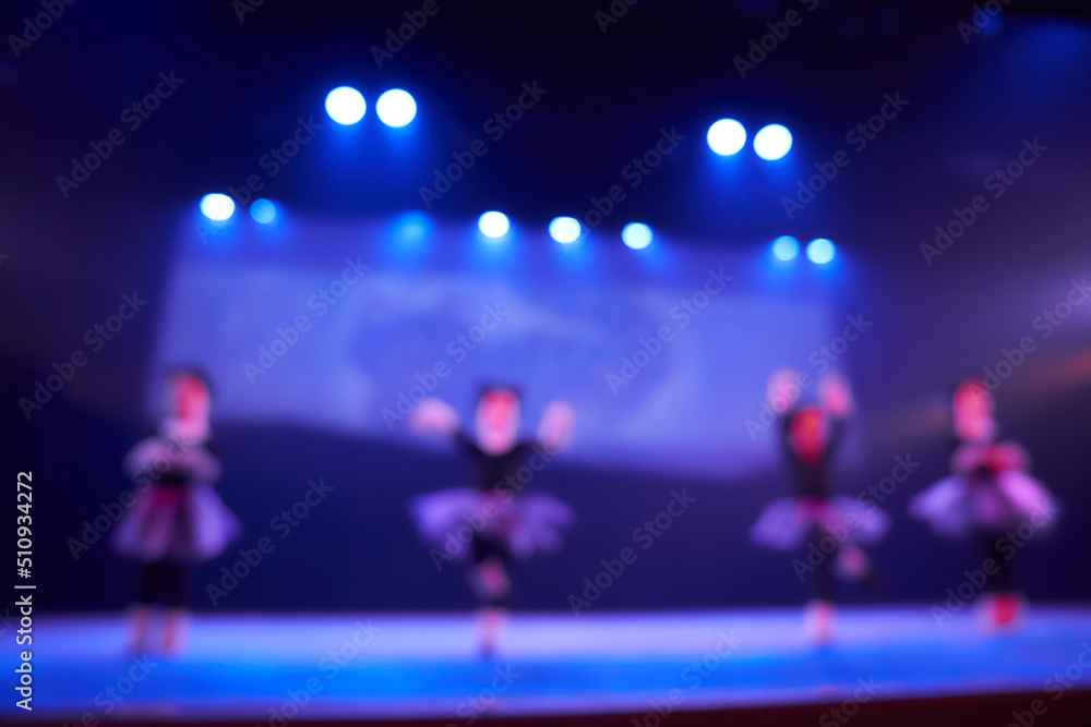 A blurry abstract background of a dance festival from a group of girls in the number of four people. Bright lighting of the blue dance floor stage. High quality photo