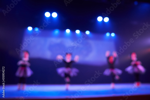A blurry abstract background of a dance festival from a group of girls in the number of four people. Bright lighting of the blue dance floor stage. High quality photo
