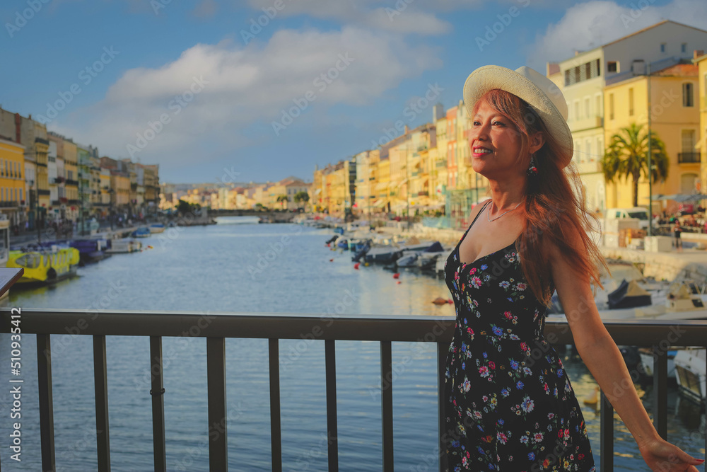 Young asain woman in summer dress standing on bridge in Sete, one of the top destination in Occitanie region, south of France