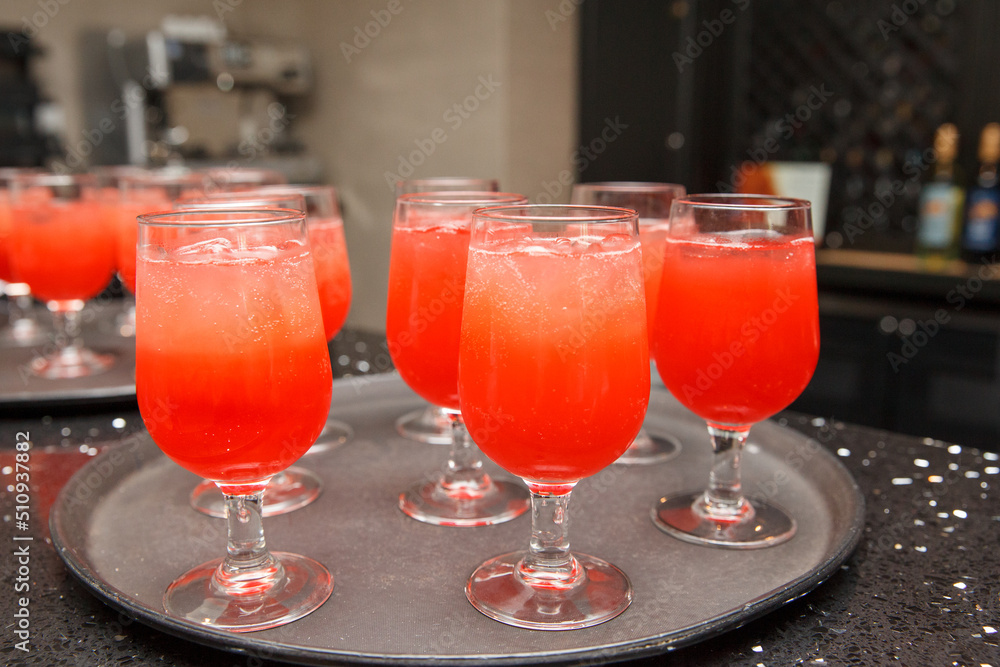 Refreshing red and orange drinks on a tray in wine glasses. Refreshing red and orange drinks on a tray in wine glasses.