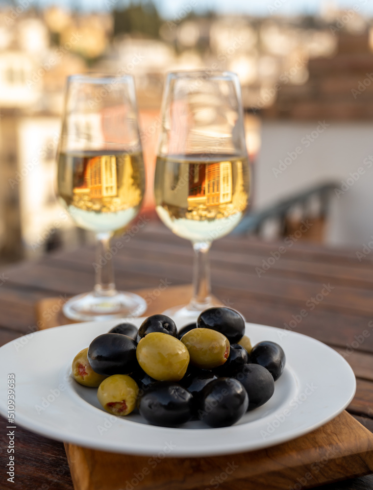 Glass bowl with black andalusian olives served with sherry wine on outdoor terrace with view on old part of Granada, Andalusia, Spain Glass bowl with black andalusian olives served with sherry wine on outdoor terrace with view on old part of Granada, Andalusia, Spain