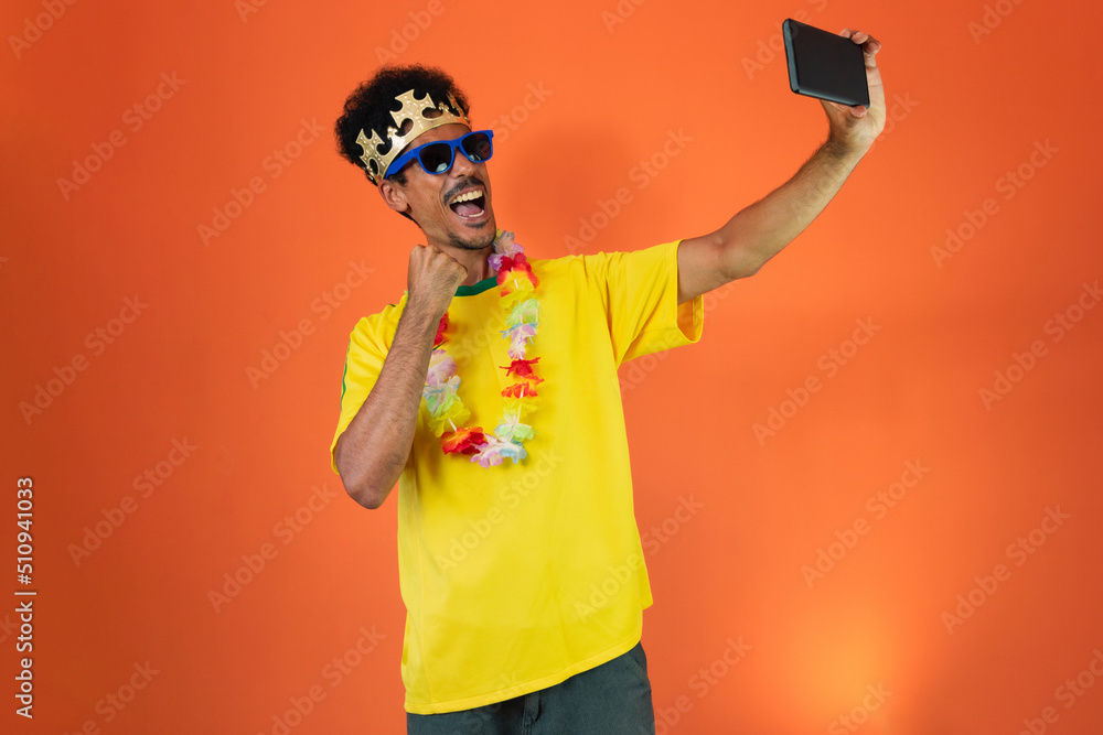 Man in yellow soccer outfit holding mobile Isolated on Orange Background. Excited football fan cheering. Man in yellow soccer outfit holding mobile Isolated on Orange Background. Excited football fan cheering.