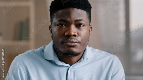 Portrait of concentrated african businessman brunet young guy with confident calm serious eyesight focused male adult person american entrepreneur millennial freelancer look at camera posing indoors