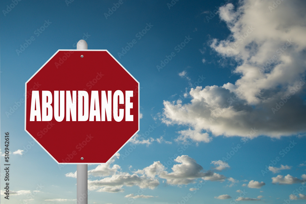 Obraz premium Red stop sign with the word Abundance on a blue sky background.