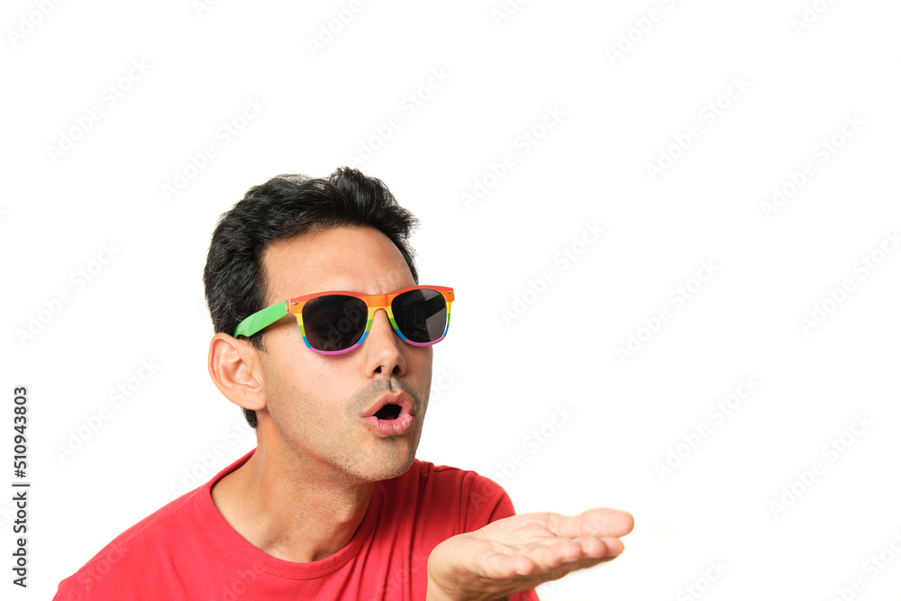 Dark-haired guy in red t-shirt blowing a kiss on his hand with lgbtq rainbow glasses Dark-haired guy in red t-shirt blowing a kiss on his hand with lgbtq rainbow glasses
