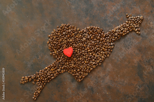 Roasted coffee beans in heart shaped bowl on dark background. Love coffee concept. Top view flat lay with copy space