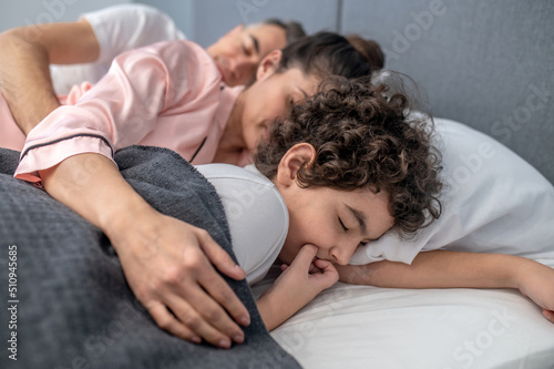Cute family sleeping together in one bed
