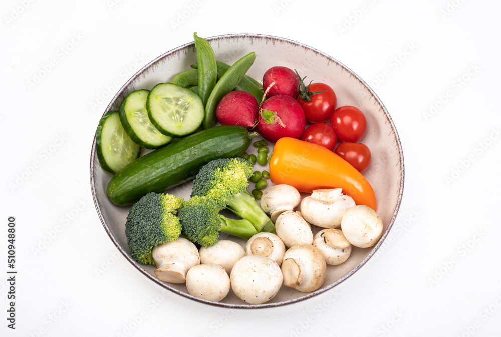 A composition of spring vegetables on a plate, isolated. Colorful veggies, top view, banner with a copy space A composition of spring vegetables on a plate, isolated. Colorful veggies, top view, banner with a copy space
