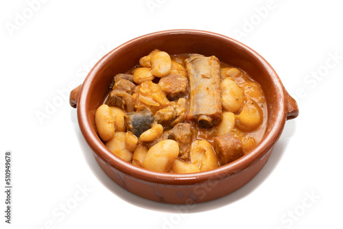 A terracotta plate with Asturian fabada, a typical Spanish bean stew, on a white background. Spanish food concept.