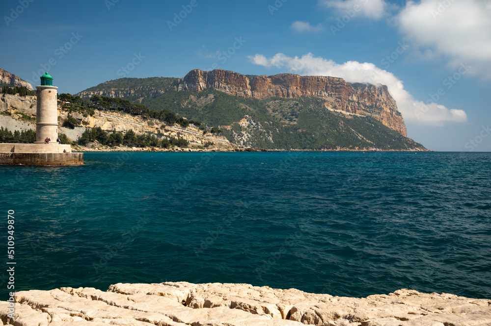 Panoramic view on cliffs, blue sea, beach, houses, streets and old fisherman's harbour with lighthouse in Cassis, Provence, France