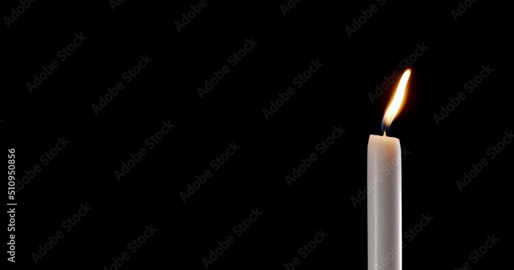A single white candle burning.Isolated candle burning with dark background.White paraffin candle with yellow shades burns on a black background.Background or illustration of remembrance or celebration A single white candle burning.Isolated candle burning with dark background.White paraffin candle with yellow shades burns on a black background.Background or illustration of remembrance or celebration