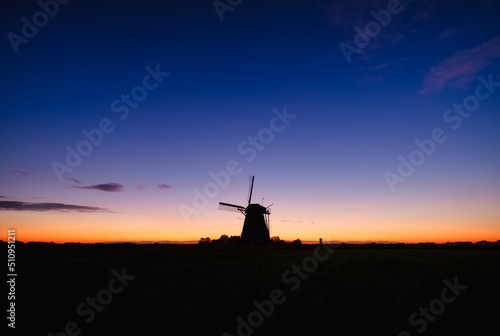 Windmills in the Netherlands. Historic buildings. Agriculture. Summer landscape during sunset. Bright sky and the silhouette of a windmill. Photography for design.